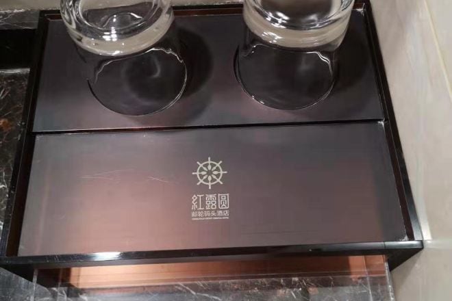 A black tray with two clear glasses on top, a logo, and text in the center.