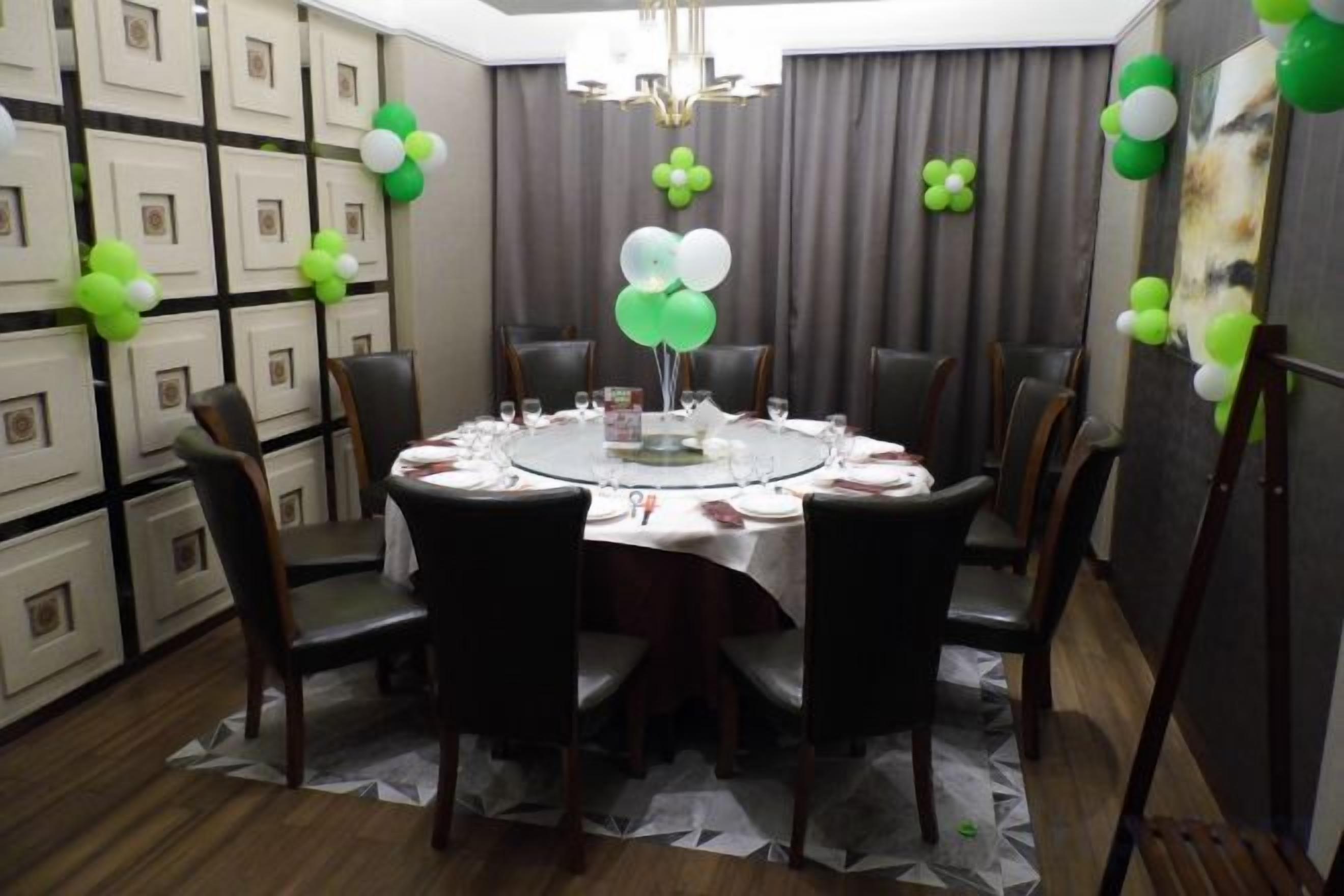 A round dining table with chairs, a chandelier, and balloons.