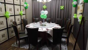 A round dining table with chairs, a chandelier, and balloons.