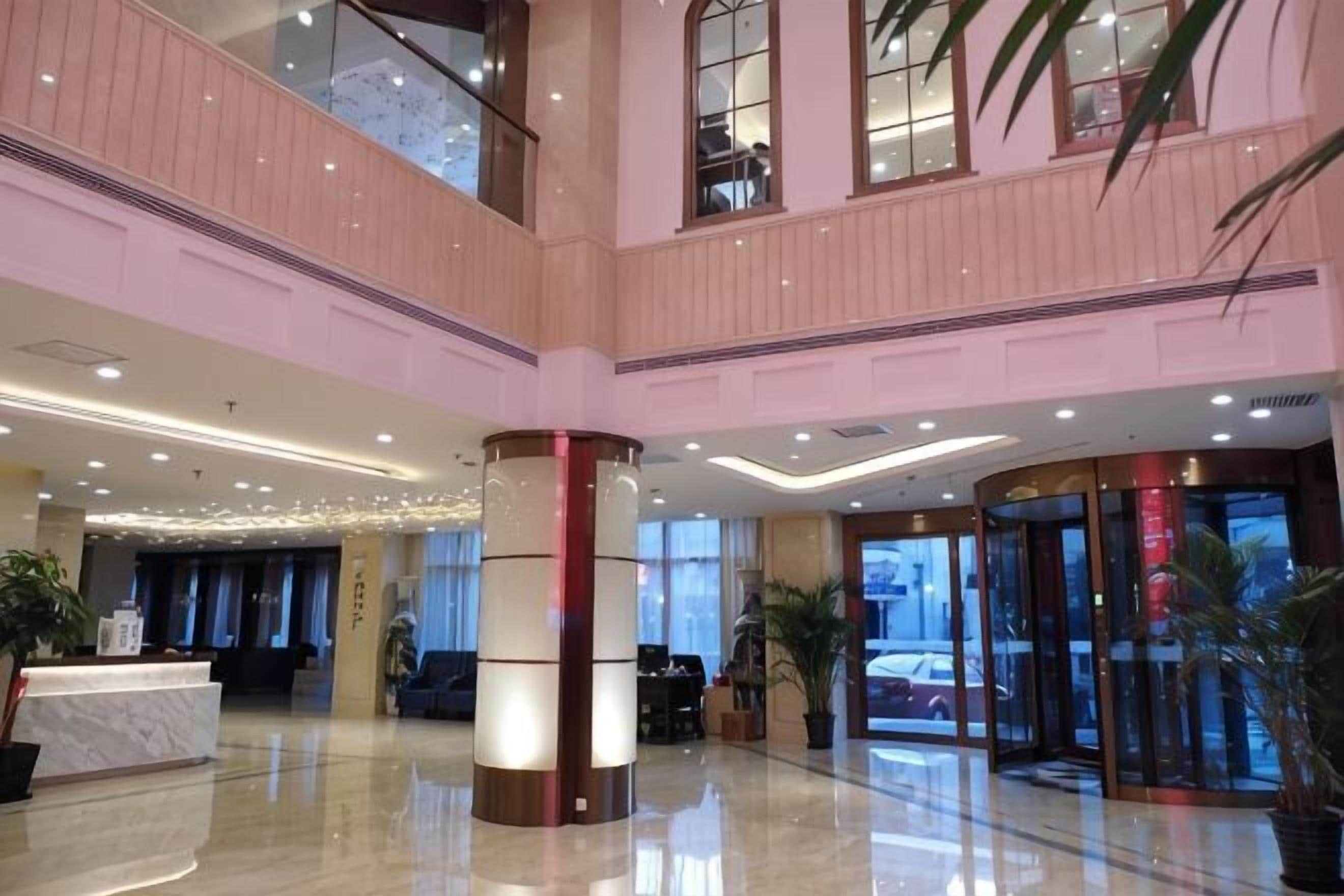 A hotel lobby with a reception desk, a double-height ceiling, and a glass elevator.