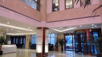 A hotel lobby with a reception desk, a double-height ceiling, and a glass elevator.