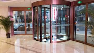 A revolving door entrance with glass panels, a potted plant, and a clean, polished floor.