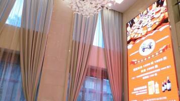 A hotel room with a large window, sheer curtains, and a ceiling light fixture.