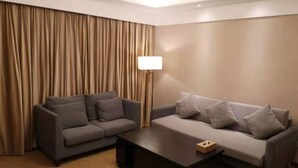 A modern hotel room with a grey sofa, a coffee table, and a floor lamp. - Hongluyuan Hotel (Shanghai)