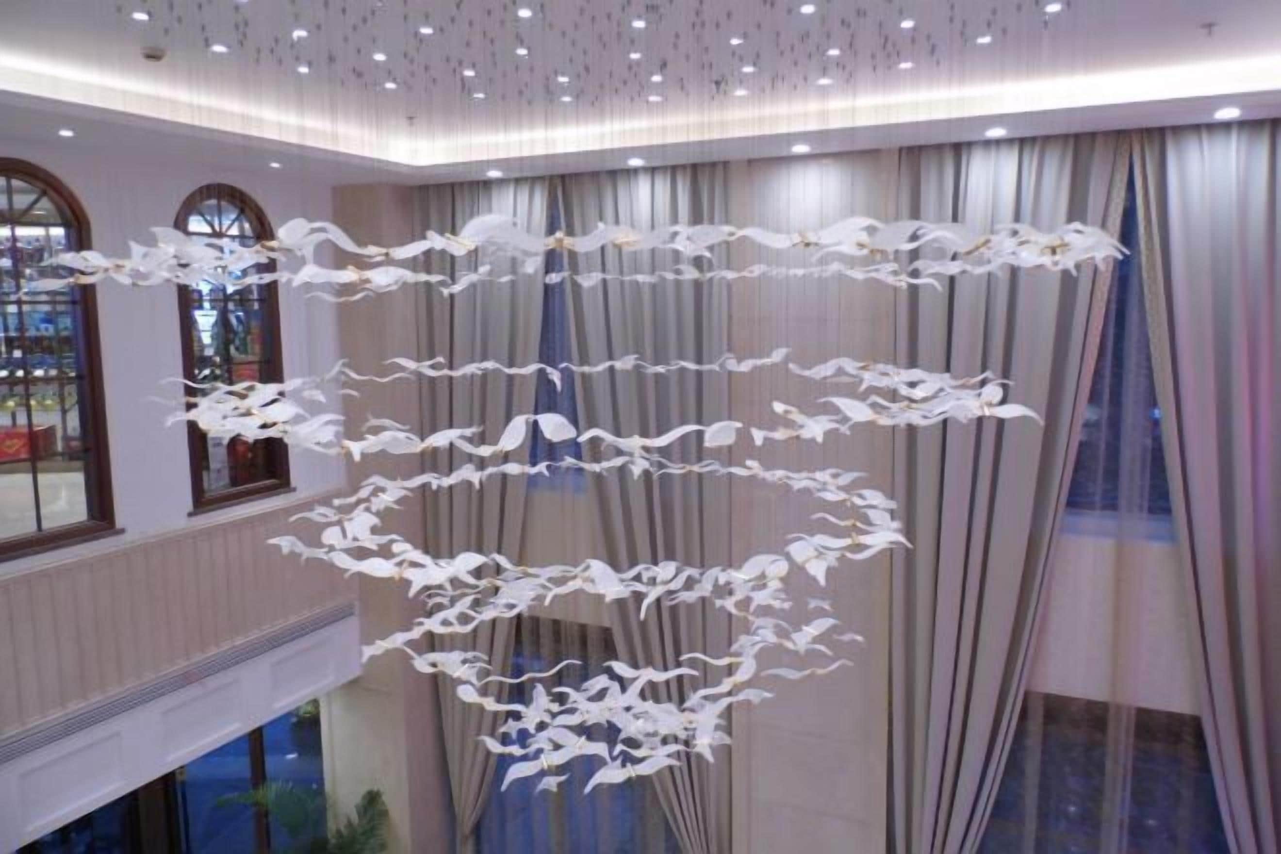 Un vestíbulo de hotel con una estructura decorativa circular y blanca que cuelga del techo.