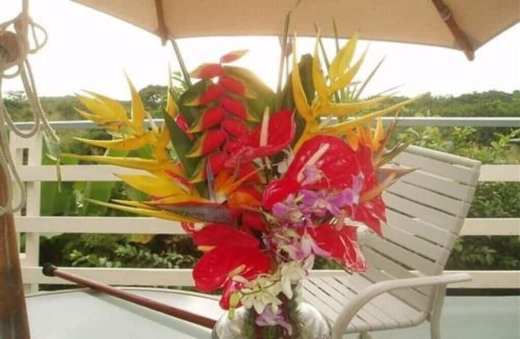 A chair with a vase of tropical flowers on a balcony.