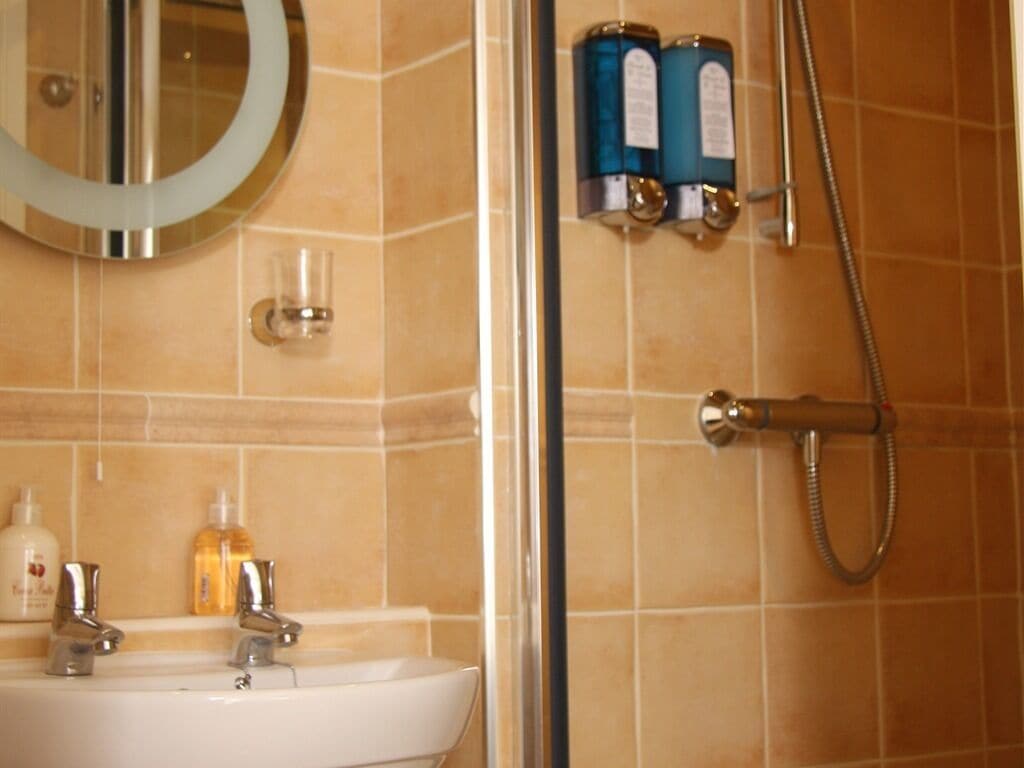 Un baño con lavamanos, espejo y ducha.
