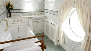 Uma casa de banho com banheira, pia e janela com cortinas.