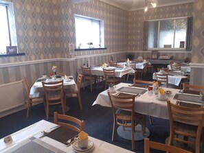 A dining area with multiple tables and chairs, each set with tableware and napkins. - Wellington Hotel (Blackpool)