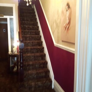 A staircase with a handrail, a wall with a painting, and a door with a sign. - Wellington Hotel (Blackpool)