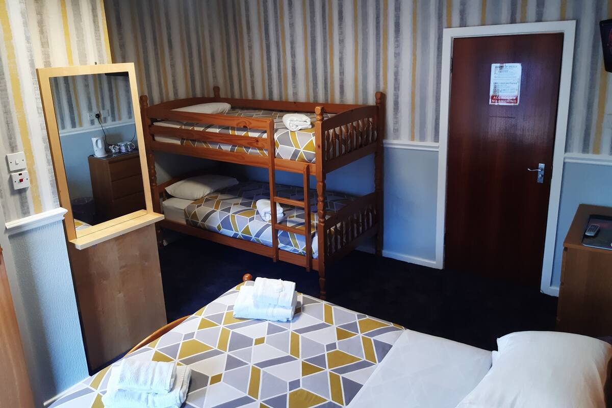 A bunk bed room with a mirror, a door with a sign, and a small table with a phone.