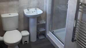 A bathroom with a toilet, sink, and shower. - Wellington Hotel (Blackpool)