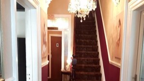 A staircase with a chandelier, a wooden floor, and a door with a sign. - Wellington Hotel (Blackpool)