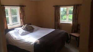 A bedroom with a large bed, two windows with curtains, a chair, and a hanging light fixture. - The Winchfield Inn (Hook)