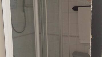 Une salle de bain avec une douche à parois de verre, des toilettes et un porte-serviettes.