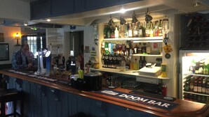 A bar area with a counter, stools, and a variety of bottles and glasses. - The Winchfield Inn (Hook)