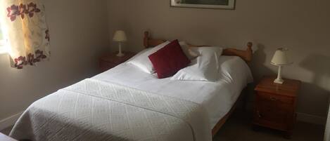 A neatly made bed with a patterned bedspread, two bedside tables with lamps, and a framed picture on the wall.