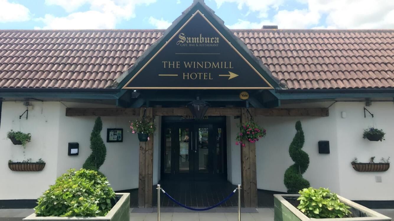 Eingang des Windmill Hotels mit einem Schild, das es als Teil des Sambura Cafe, Bar & Restaurant kennzeichnet.