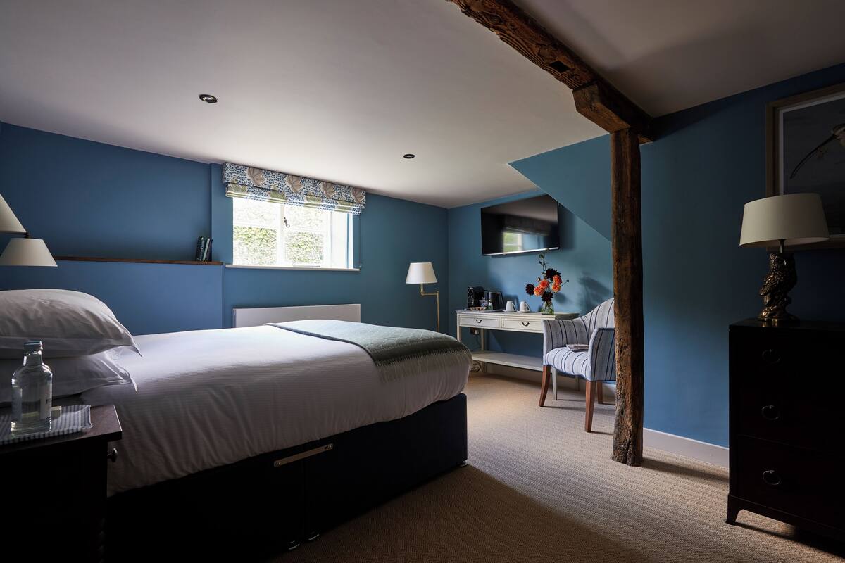 A bedroom with a bed, desk, chair, and dresser.