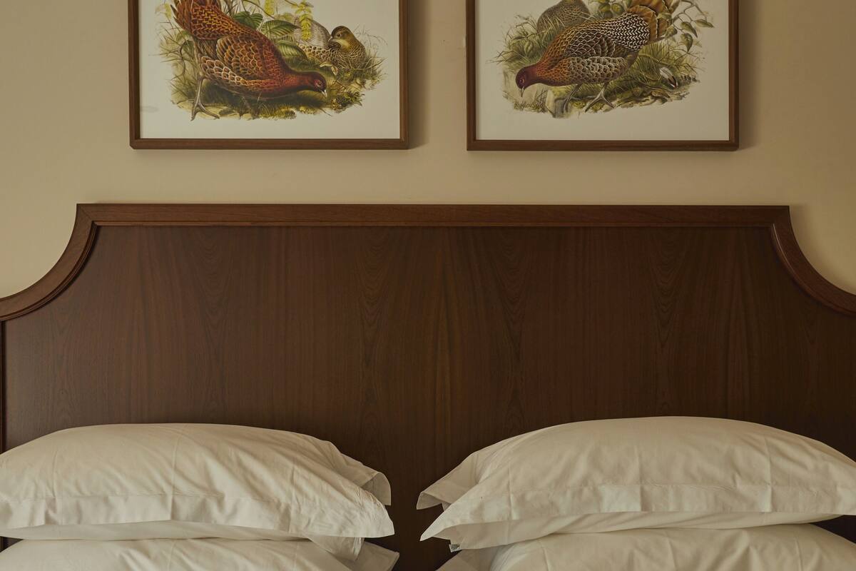 A bed with white linens and a wooden headboard.