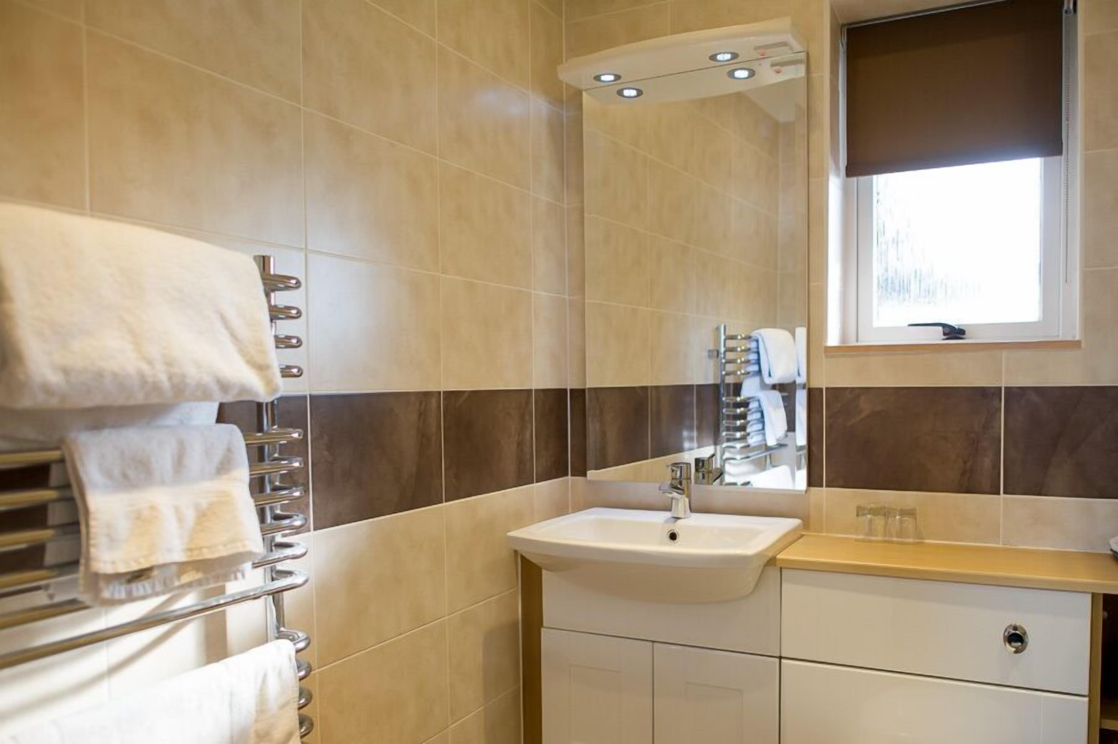 Un baño moderno con lavamanos, espejo, toallero y ventana con vistas.