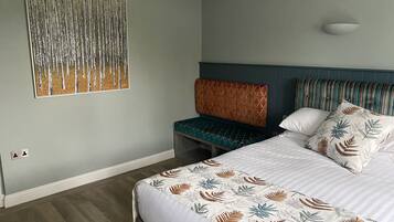 Une chambre d’hôtel avec un lit, un banc et une œuvre d’art accrochée au mur.