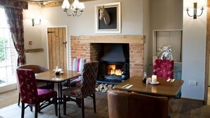 Un comedor acogedor con chimenea de ladrillo, vigas de madera y un trofeo de caza.