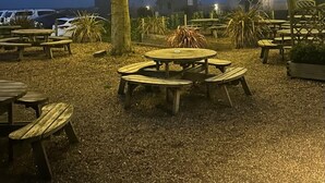 Un espacio al aire libre con mesas de picnic y luces colgantes en los árboles.