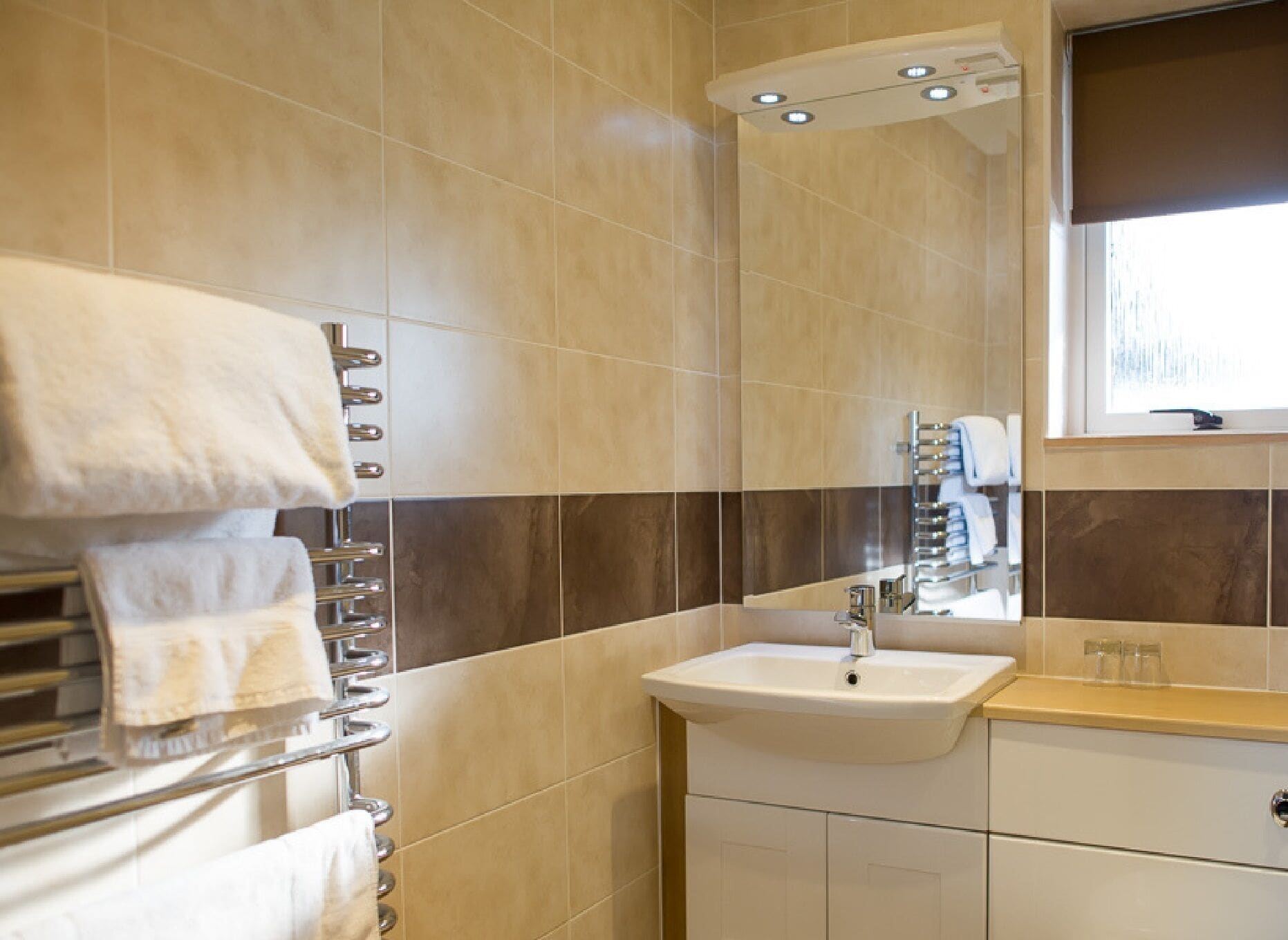 A bathroom with a sink, mirror, towel rack, and a window.