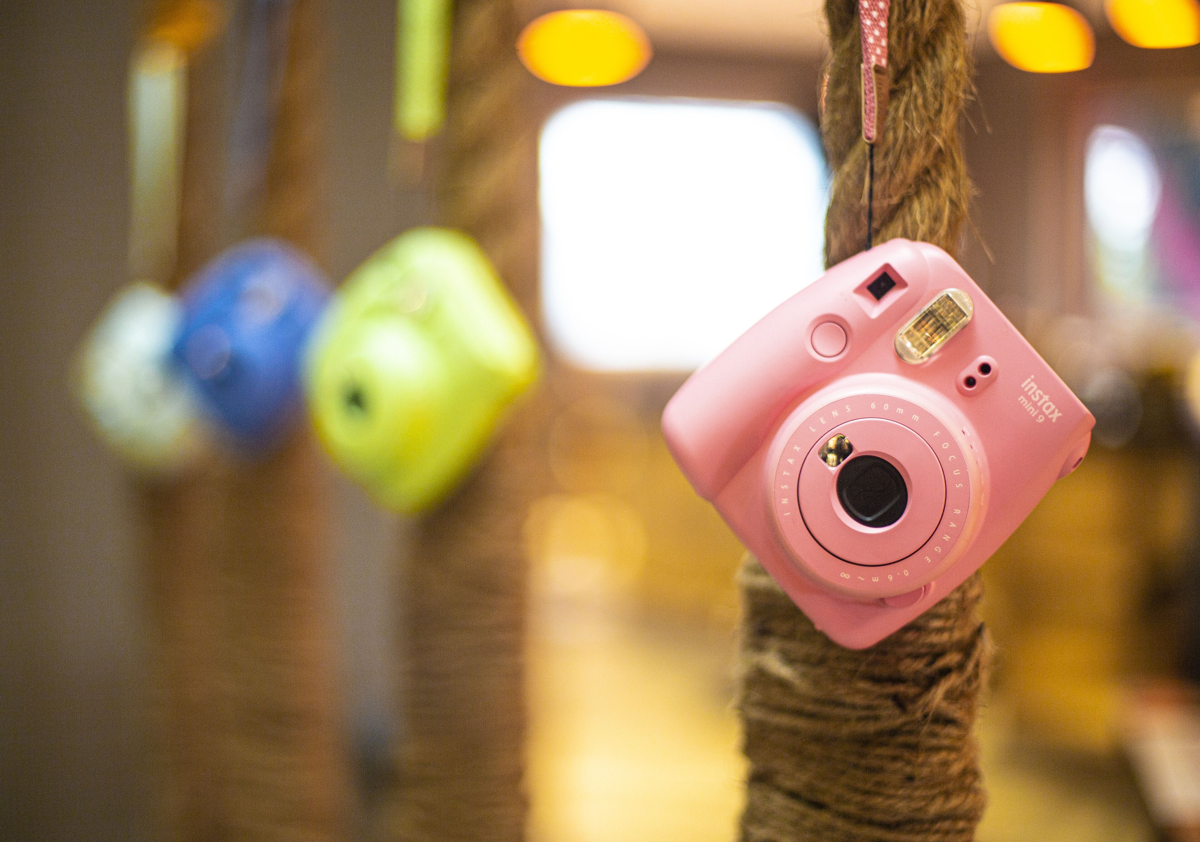 A pink camera hanging on a rope.