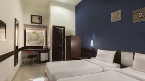 Una camera d'albergo con due letti, una scrivania, una sedia e un armadio.