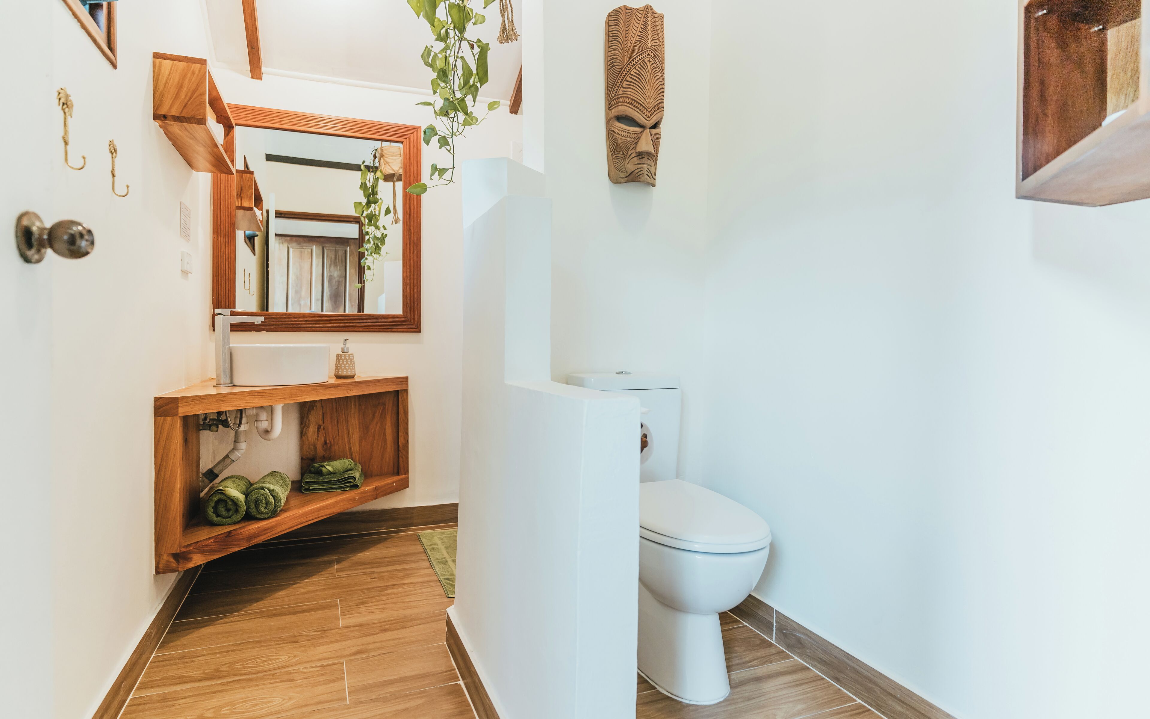 Une salle de bain avec un meuble-lavabo en bois, des toilettes blanches et un miroir au-dessus du lavabo.