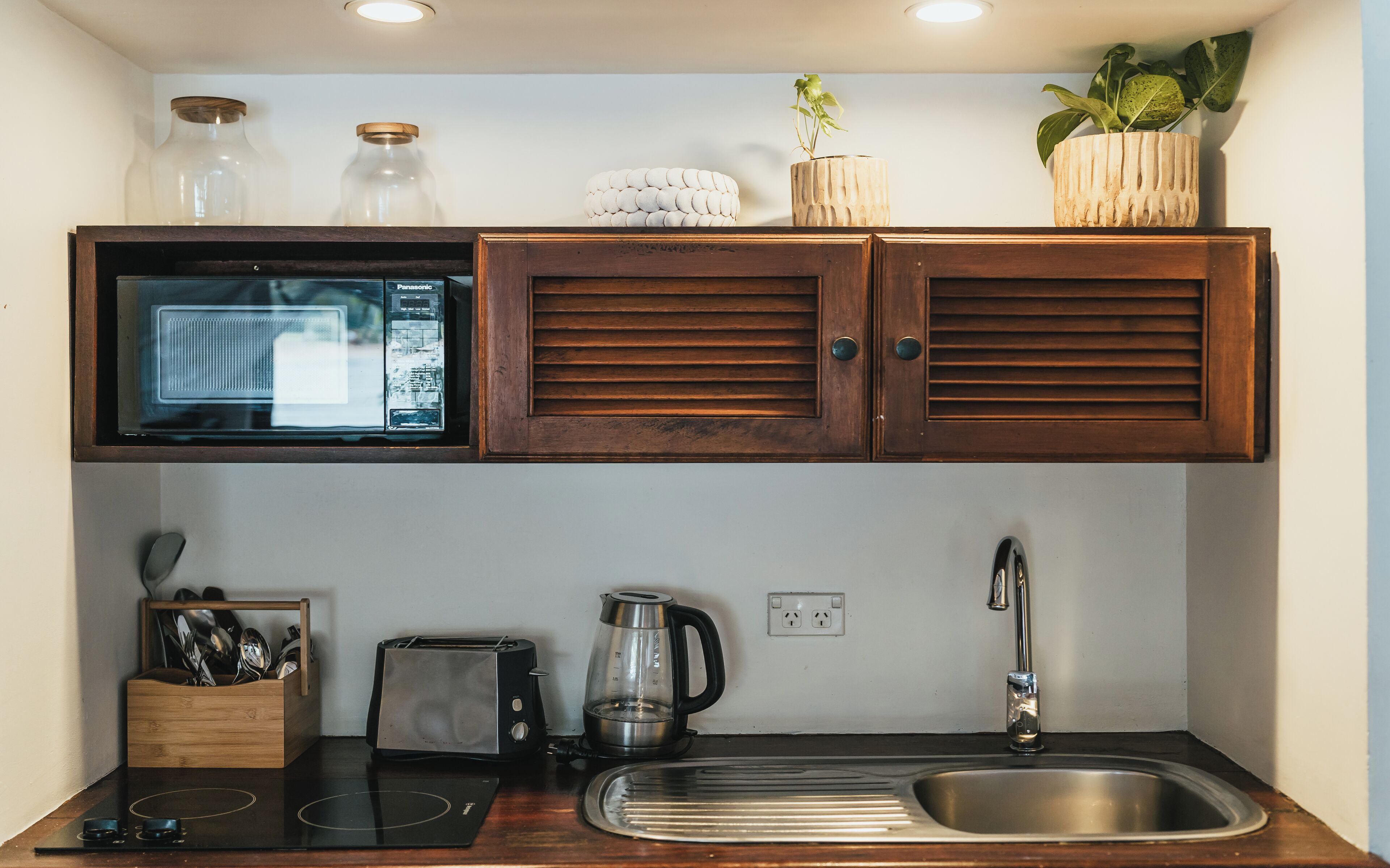 Una cocina compacta equipada con microondas, tostadora, hervidor y pileta.