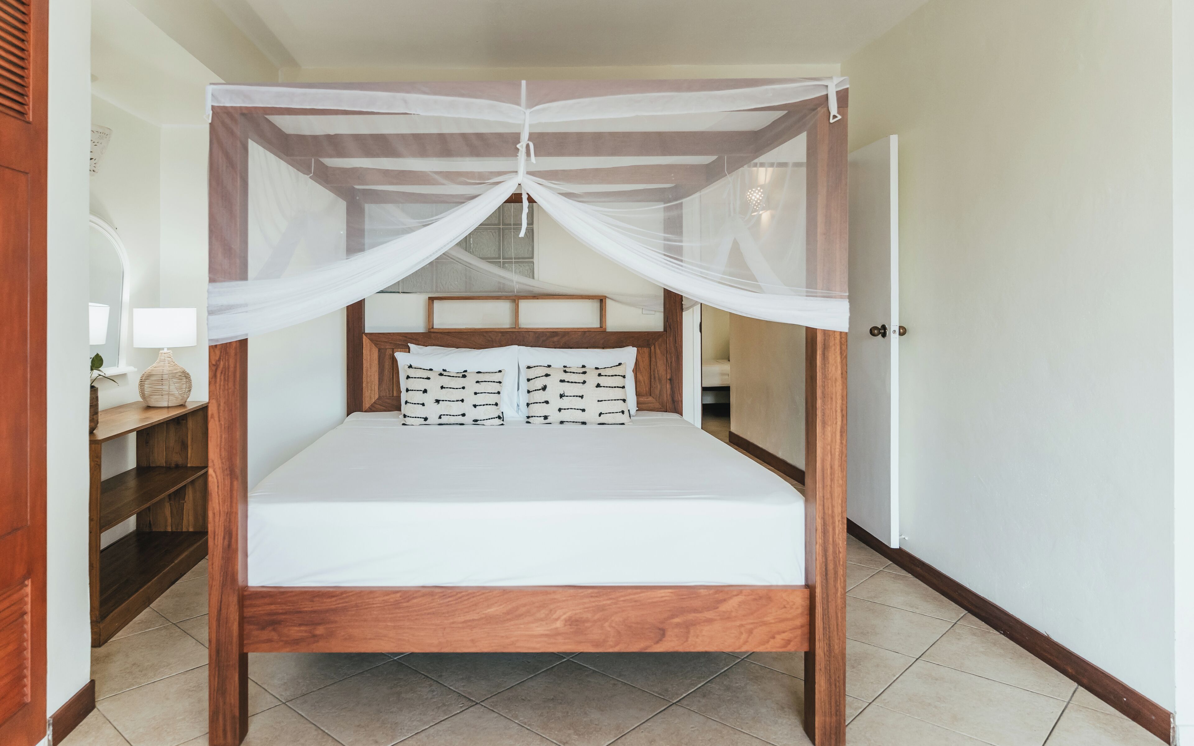 Una cama con dosel, una mesita de noche con lámpara y un espejo.