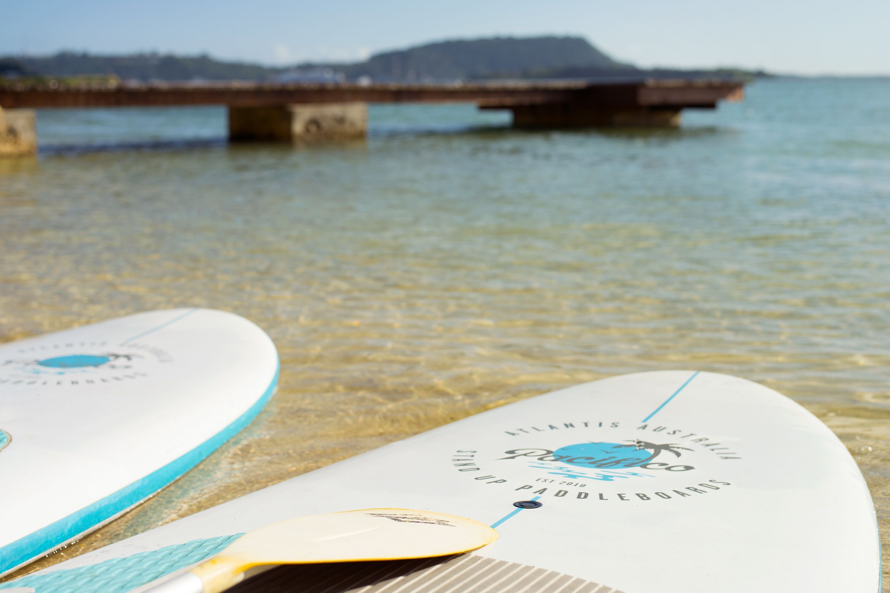 Two surfboards on a wooden dock with a bridge in the background.