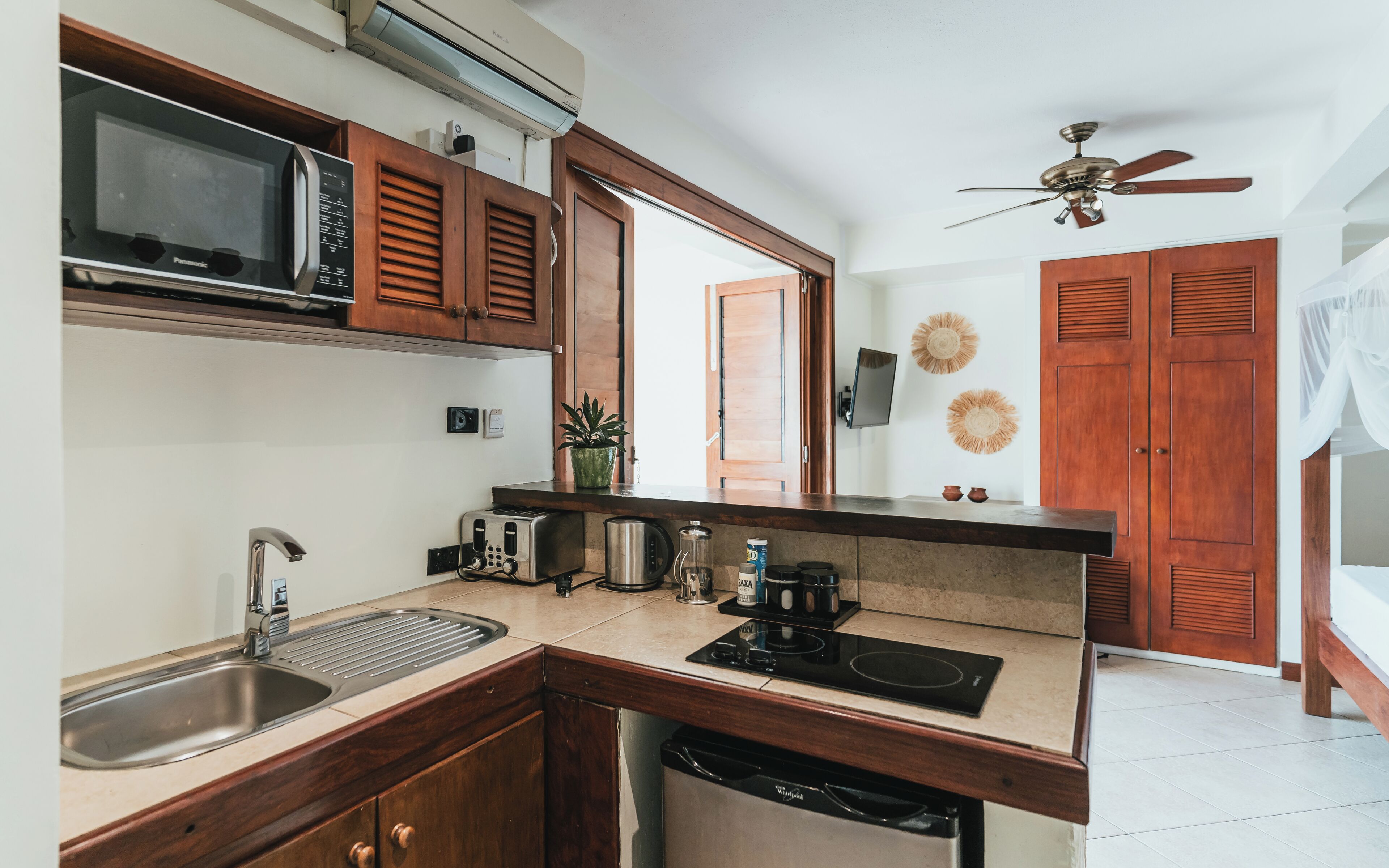 A kitchen with a microwave, toaster, sink, and a ceiling fan.