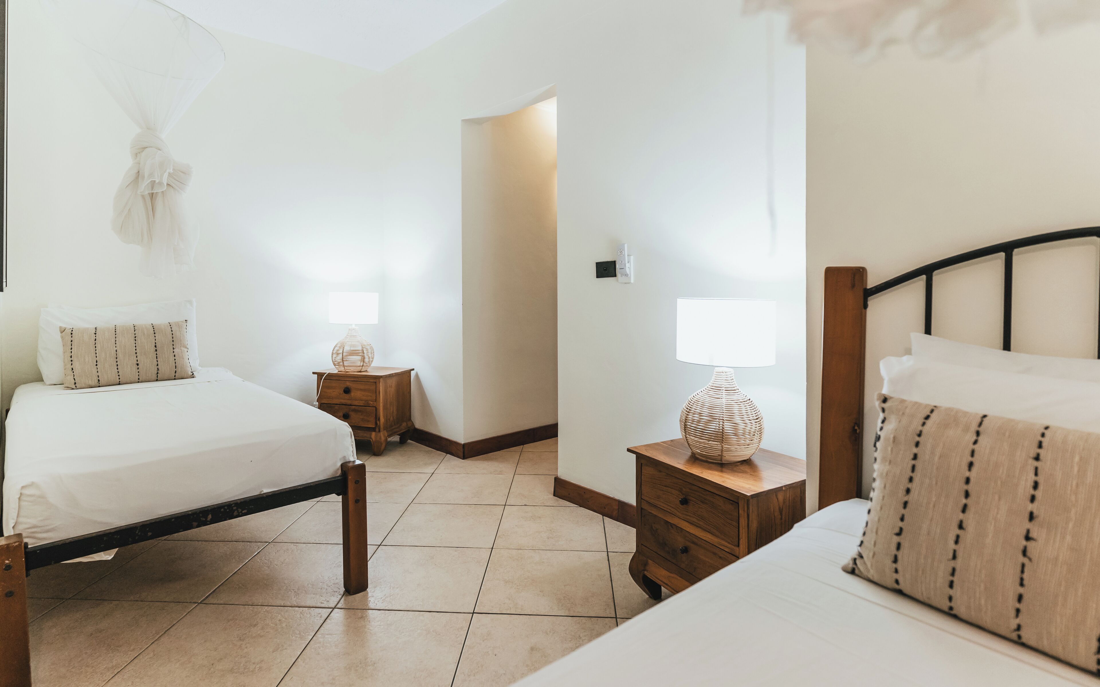Una habitación de hotel con dos camas, mesitas de noche de madera y lámparas de noche.
