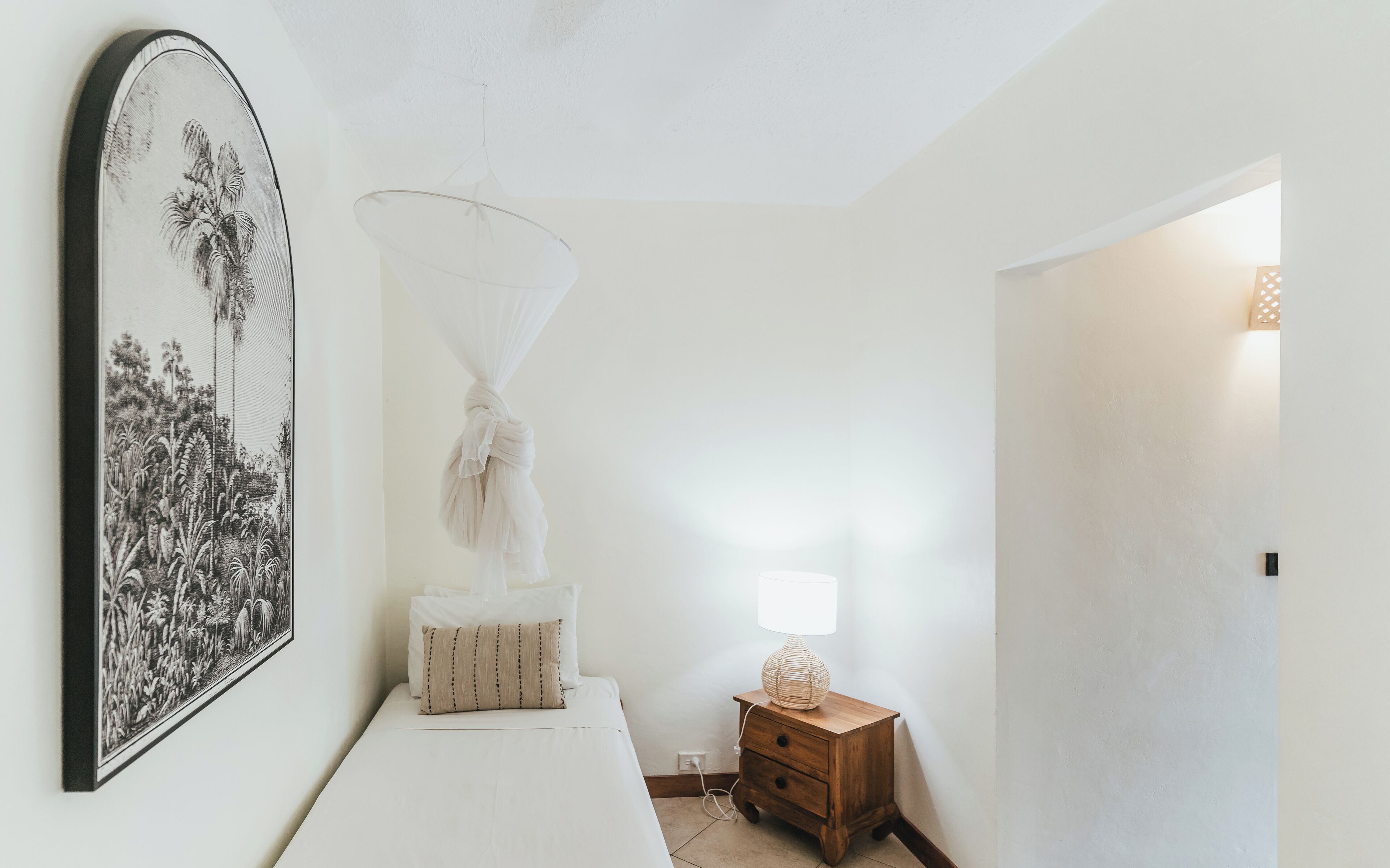 A bedroom with a bed, a nightstand, a lamp, and a wall-mounted artwork.