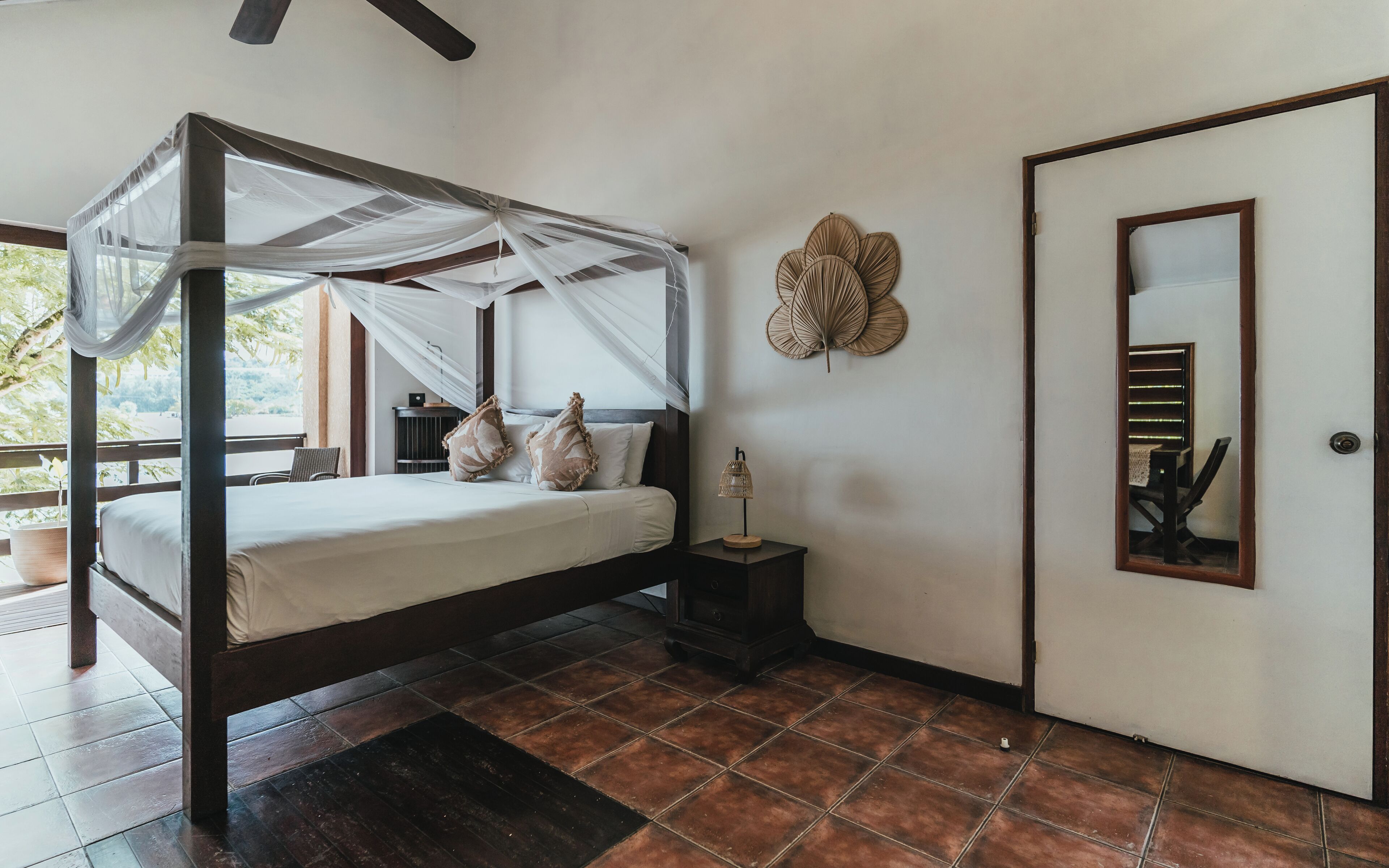 A room with a bed, a nightstand, a door, and a wall decoration.