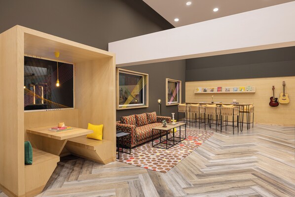 A modern living room with a sofa, coffee table, and a dining area with chairs. - Ginger Ahmedabad Vastrapur (Ahmedabad)