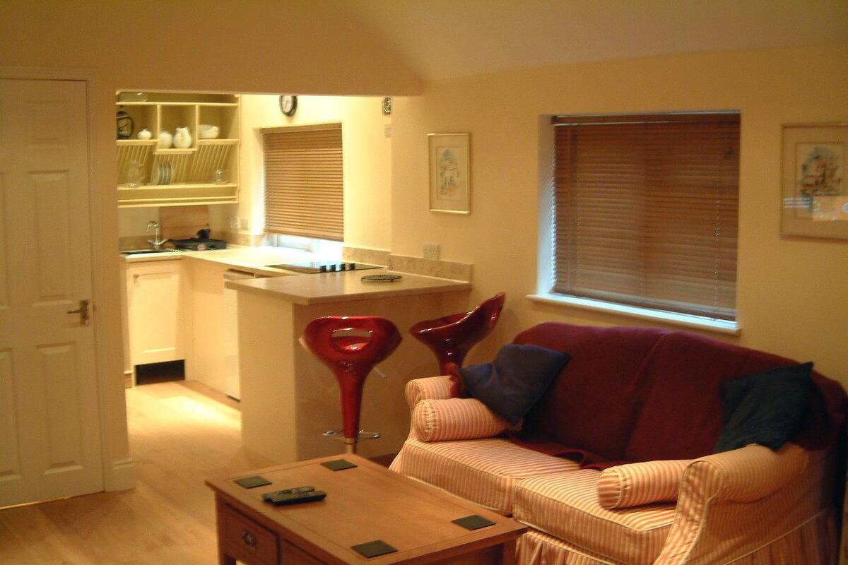 A living room with a sofa, a coffee table, and a kitchen area in the background.