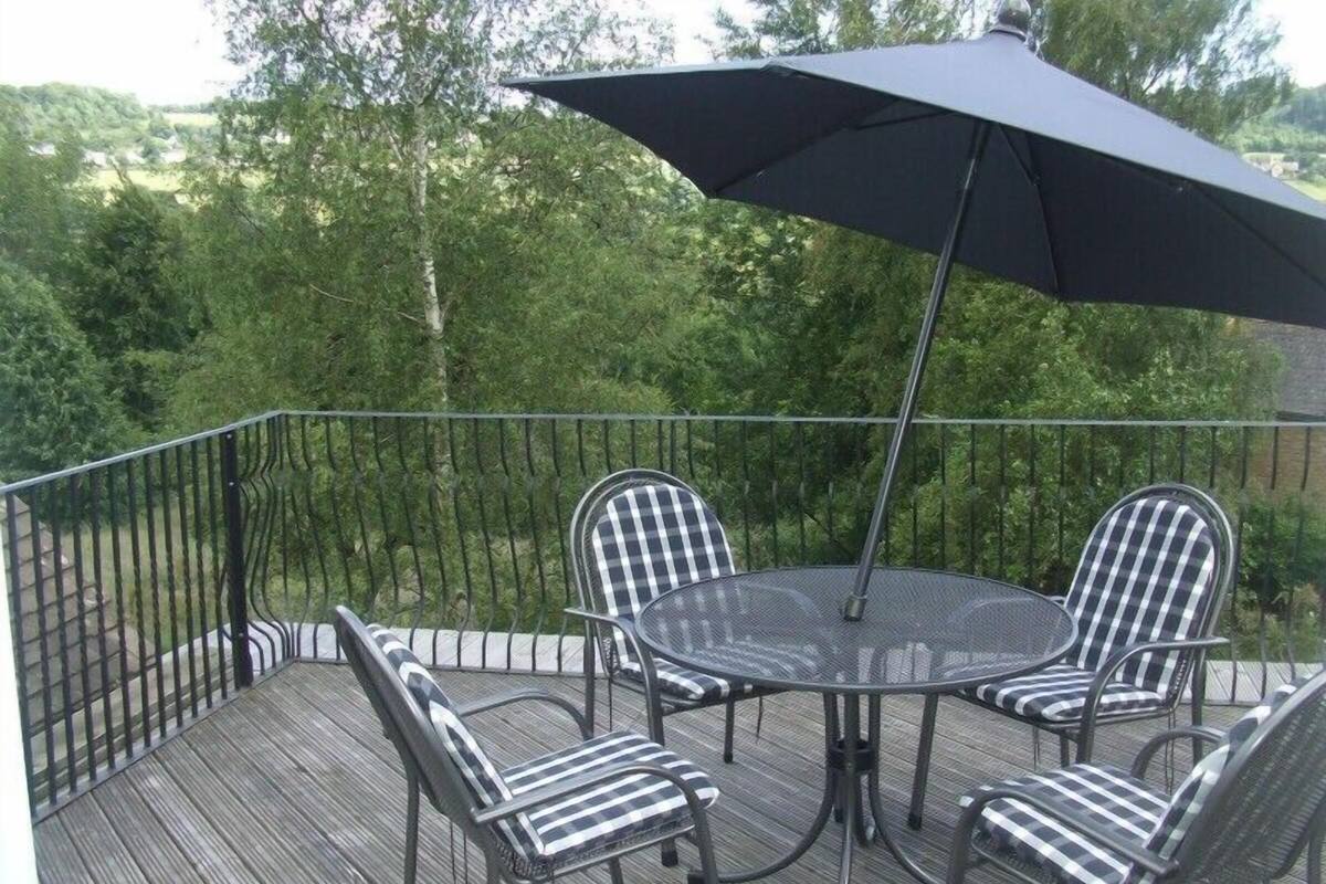 A deck with a round table and four chairs, surrounded by a metal railing.