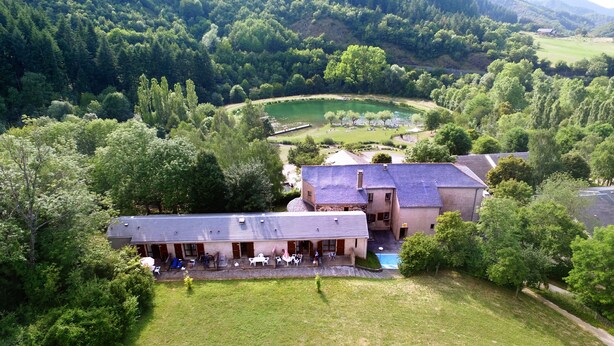 A large building with a courtyard, surrounded by lush greenery and a lake. - VVF Sud Aveyron, Brusque (Brusque)