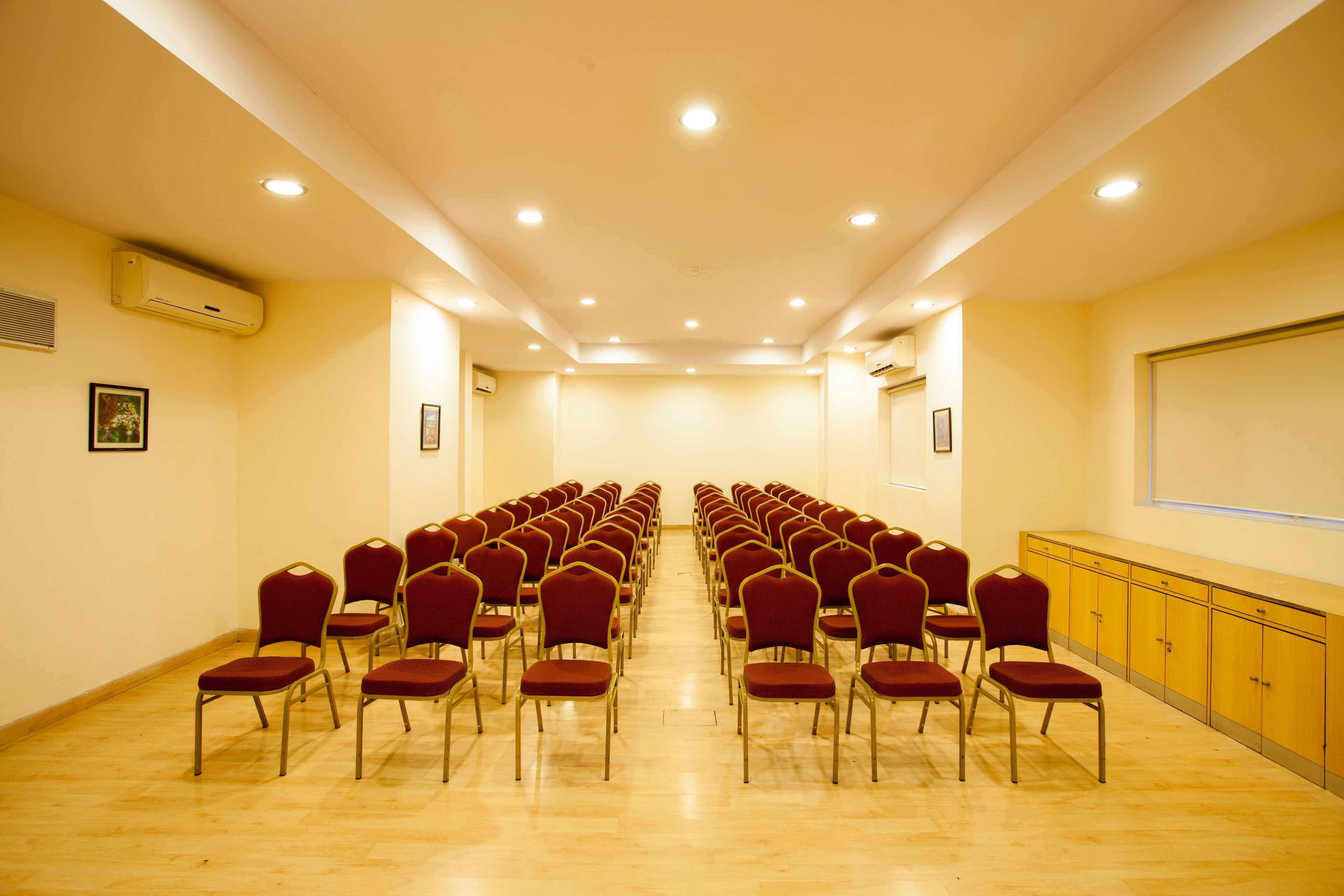 A conference room with rows of red chairs, a projector screen, and a yellow cabinet.