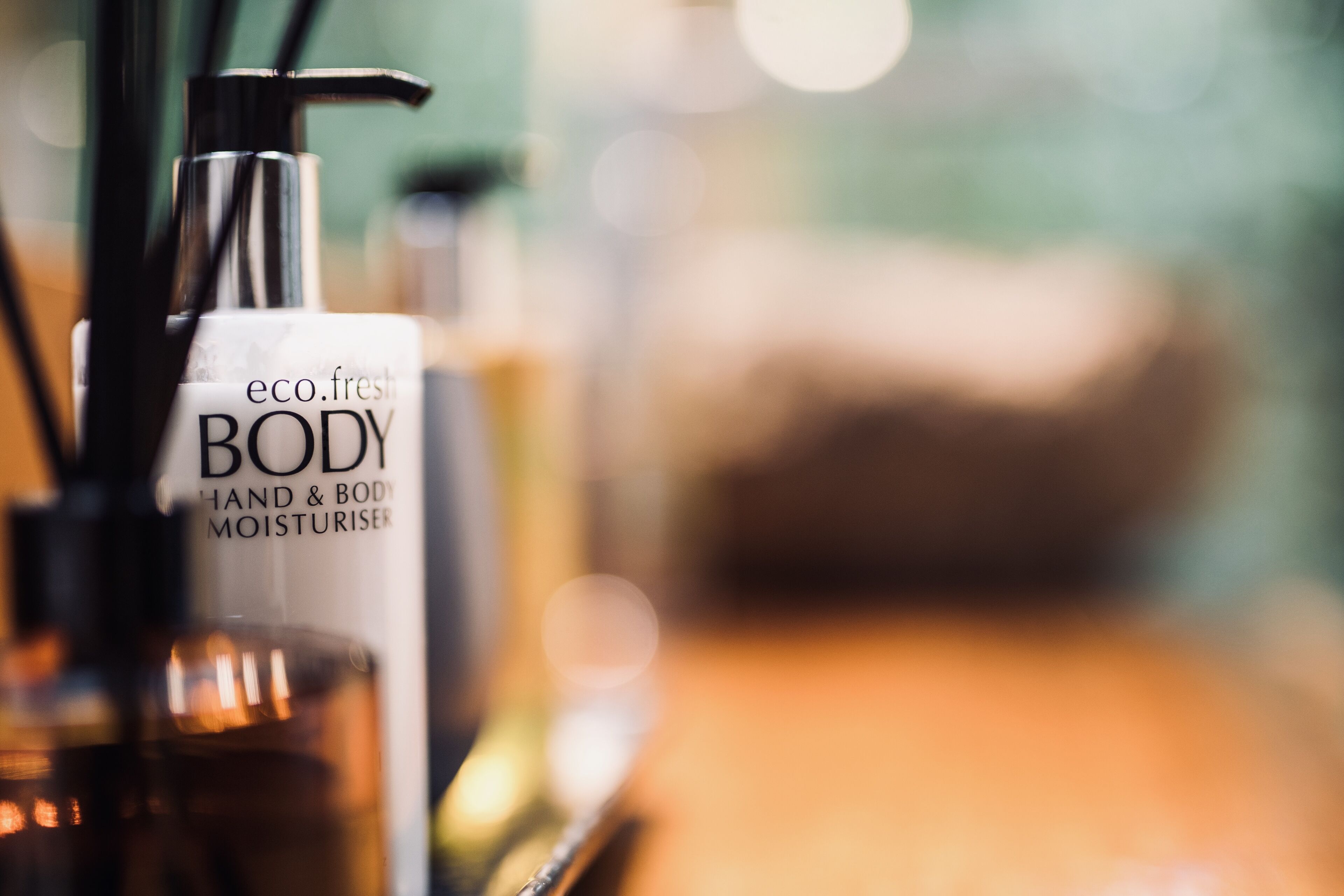 A close-up of a bottle labeled "eco.fresh BODY HAND & BODY MOISTURISER" with a pump dispenser.