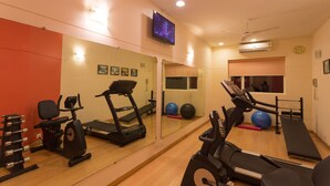 A gym with exercise equipment, a television, and a mirror. - Ginger Mangalore (Mangaluru)