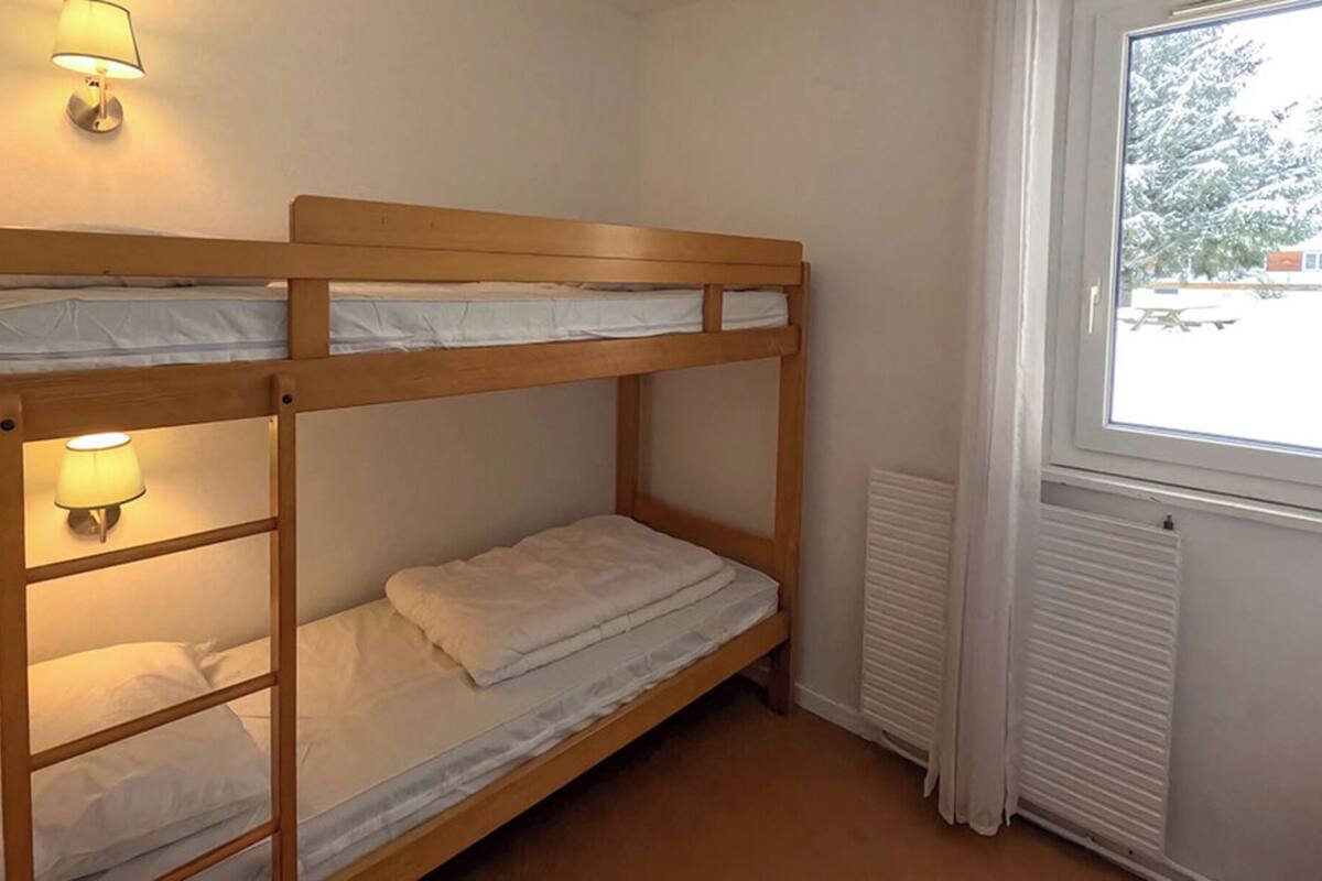 A bunk bed room with a window and a radiator.