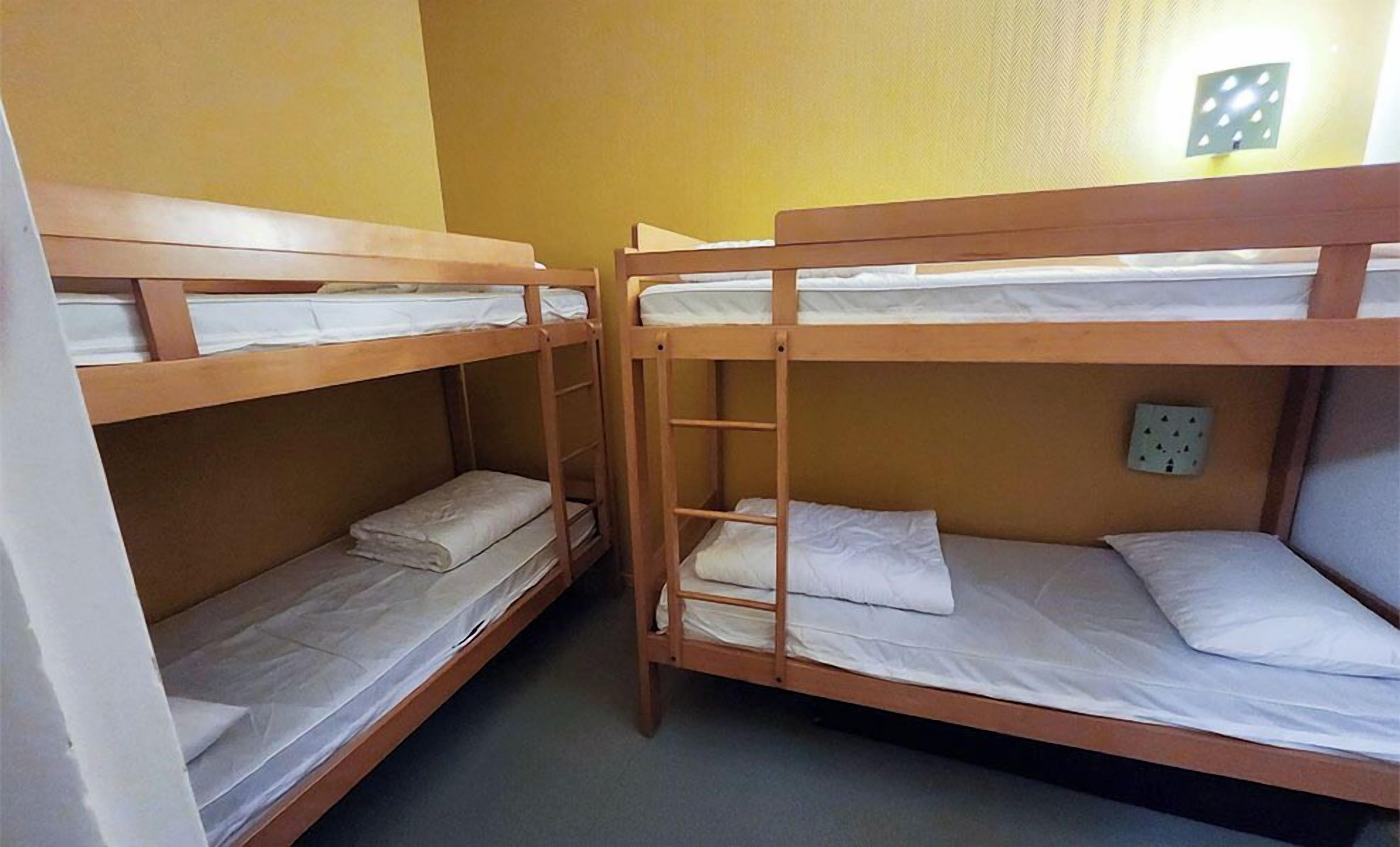 A bunk bed room with wooden frames and white bedding.