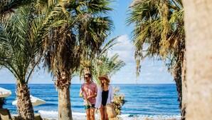 Una pareja caminando por un sendero con palmeras y vistas a la playa.