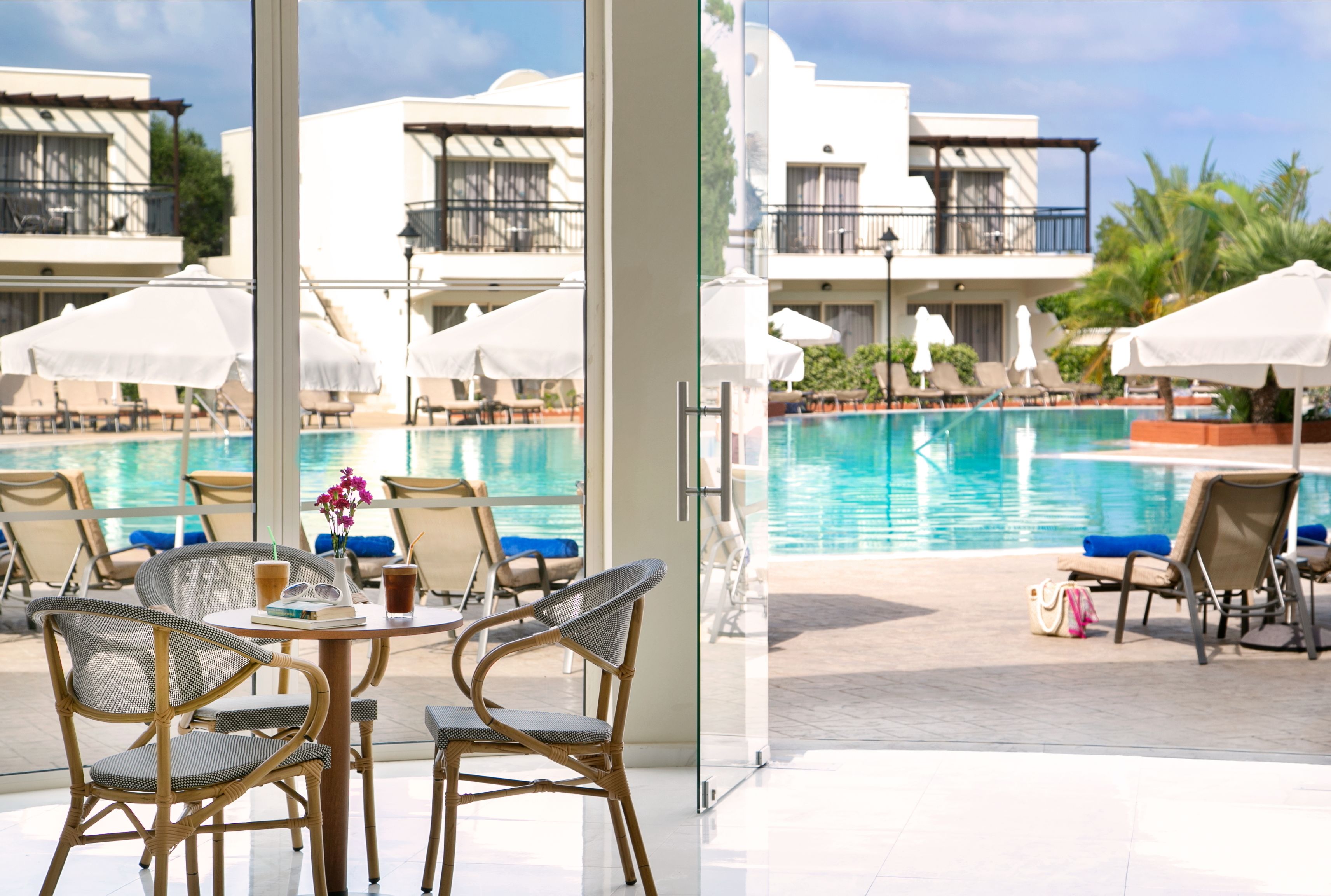 A poolside area with wicker chairs, umbrellas, and a view of a swimming pool.